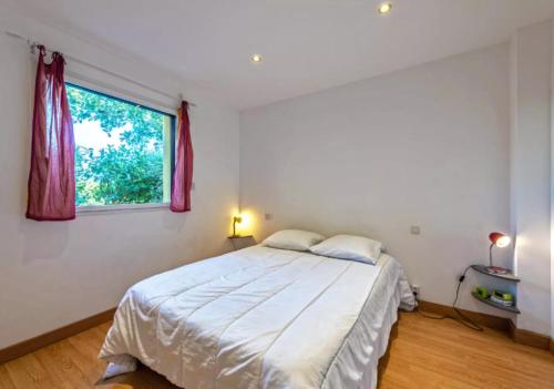 ein weißes Schlafzimmer mit einem Bett und einem Fenster in der Unterkunft Locqui in Locquirec