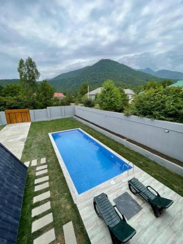 a swimming pool with two lawn chairs next to at Qafqaz Wood Chalet in Gabala