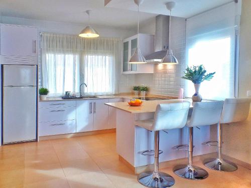 uma cozinha com armários brancos e uma ilha com bancos de bar em Casa en Cortiñan em Bergondo