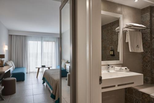 Atlantica Aeneas Resort في أيا نابا: غرفة الفندق بسرير ومغسلة ومرآة