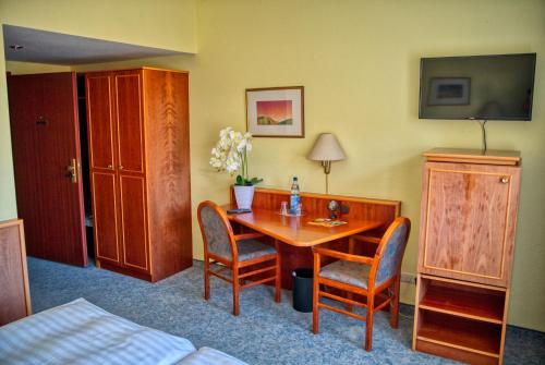ein Hotelzimmer mit einem Holztisch und Stühlen in der Unterkunft Hotel National in Bad Düben