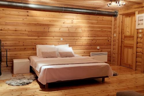 sypialnia z łóżkiem w drewnianej ścianie w obiekcie Chalet Aroania w Kalawricie