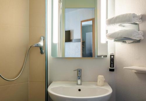 a bathroom with a sink and a mirror at B&B HOTEL Annecy Argonay in Argonay