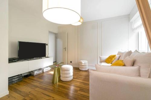 Il comprend un salon doté d'un canapé blanc et d'une télévision à écran plat. dans l'établissement Jardin Wilson, à Dijon
