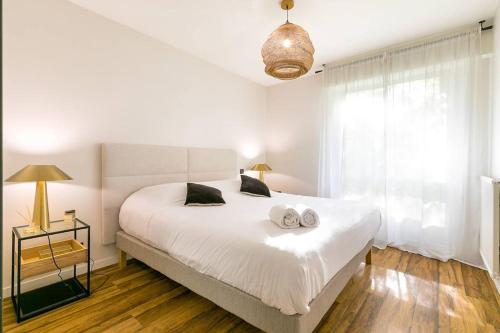 une chambre avec un lit blanc avec deux serviettes dessus dans l'établissement Jardin Wilson, à Dijon