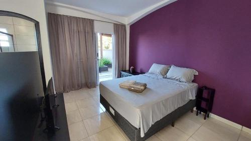 una camera con una parete viola e un letto di Estúdios Jardim Emília a Sorocaba