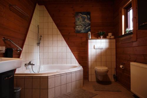 a bathroom with a tub and a toilet and a sink at Holzblockhaus, Eifel in Oberkail