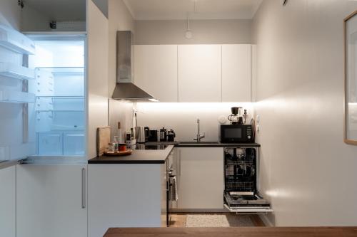 a kitchen with white cabinets and a black counter top at FREDA - Relaxing downtown studio in Helsinki