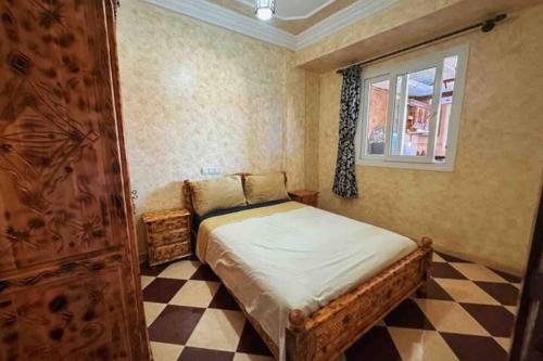 een slaapkamer met een bed en een geruite vloer bij Appartement Tamraght 2 in Tamraght Ouzdar