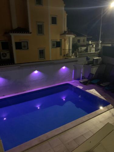 una piscina azul con luces en el balcón por la noche en Romantic room in house with pool en Seixal