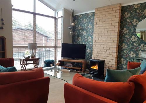 a living room with a tv and a fireplace at Willow Lodge Auchterarder in Auchterarder