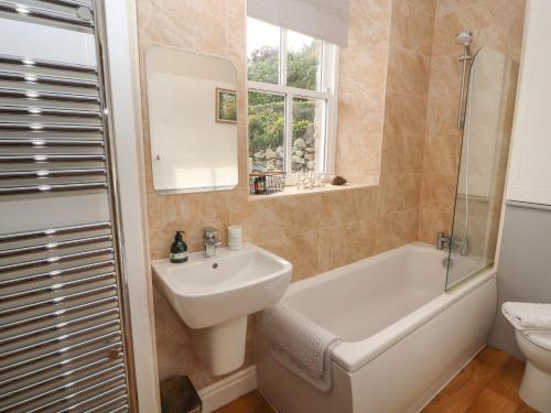 a bathroom with a sink and a tub and a toilet at 3 Tower View in Grange Over Sands