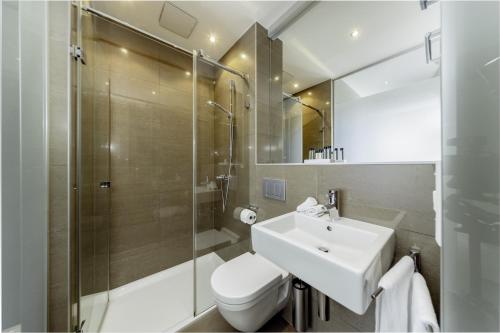 a bathroom with a toilet and a sink and a shower at Hotel Mia Zia in Belvaux