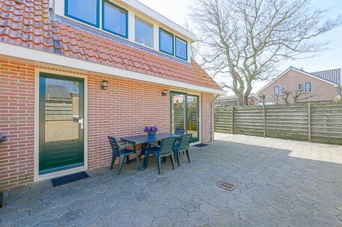 um pátio com uma mesa e cadeiras em frente a uma casa em Vakantiehuis Guja - Callantsoog em Callantsoog