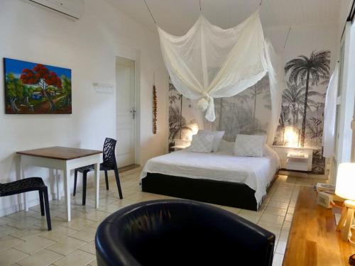 um quarto com uma cama, uma secretária e uma mesa em MANGOBELO entre océan et rivières em Capesterre-Belle-Eau
