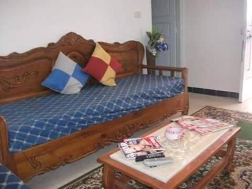 a wooden bed with pillows and a table in a room at Diar Karim Djerba in Midoun