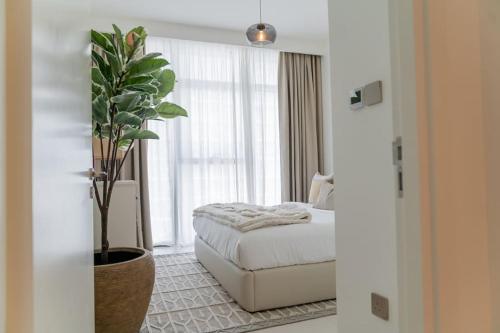 - une chambre avec un lit et une plante en pot dans l'établissement Clever Guest Beach Vista 1, à Dubaï