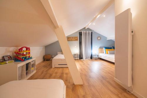 a attic bedroom with two beds and a room with wooden floors at Maison Macaron 10min Disneyland Paris in Bailly-Romainvilliers