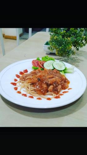 a plate of food with noodles and vegetables on a table at Votel Hotel De'Pratnya Kediri in Kediri