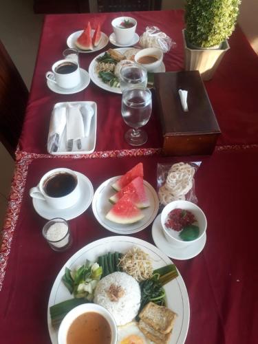 a table with plates of food on a red table at Votel Hotel De'Pratnya Kediri in Kediri