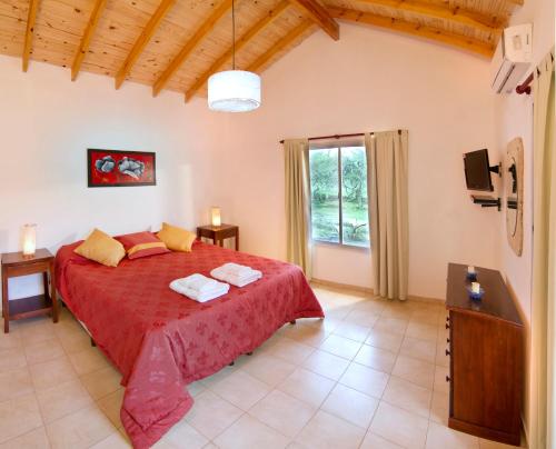 1 dormitorio con cama roja y ventana en La Faustina Casas de Campo en Villa General Belgrano