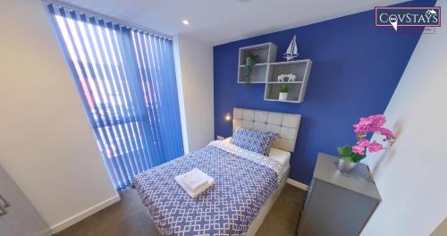 um quarto com uma cama e uma parede azul em Signature House - Contemporary Studios in Coventry City Centre, free parking, by COVSTAYS em Coventry