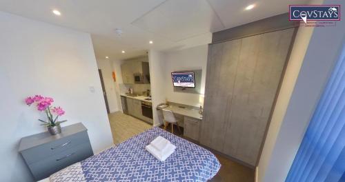 a room with a bed and a desk and a television at Signature House - Contemporary Studios in Coventry City Centre, free parking, by COVSTAYS in Coventry