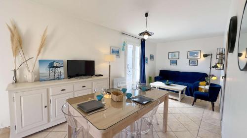 un salon avec une table et un canapé bleu dans l'établissement Petite villa individuelle, de plain pied, face aux champs et à proximité de la plage, à La Couarde-sur-Mer