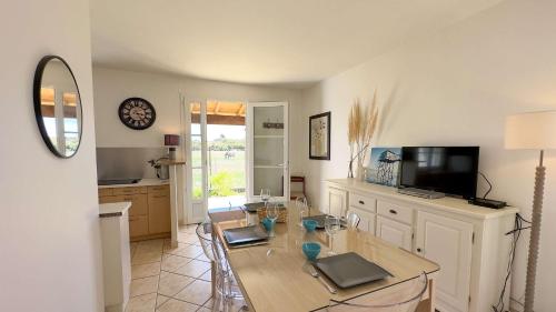 une salle à manger avec une table et une télévision dans l'établissement Petite villa individuelle, de plain pied, face aux champs et à proximité de la plage, à La Couarde-sur-Mer
