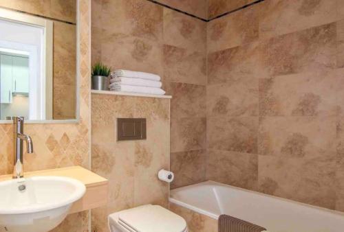 a bathroom with a sink and a tub and a toilet at Luxury Apartment/ Sea views/Pool/Gym in San Jorge