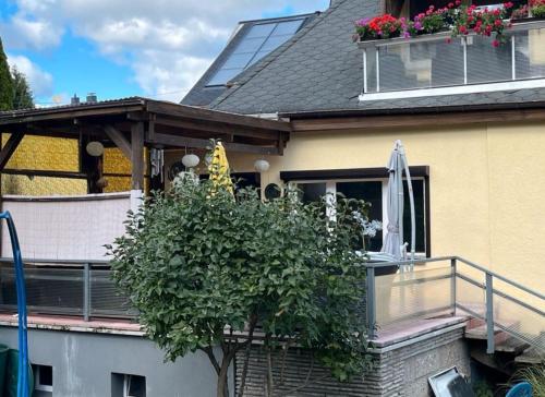 ein Haus mit einem Balkon mit einem Baum und einem Sonnenschirm in der Unterkunft Ferienwohnung in Ehrenfriedersdorf in Ehrenfriedersdorf