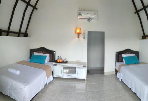 1 Schlafzimmer mit 2 Betten und blauen Kissen in der Unterkunft D'Liwatan Bungalow in Masbagik