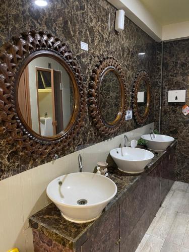 a bathroom with two sinks and two mirrors at Votel Hotel De'Pratnya Kediri in Kediri