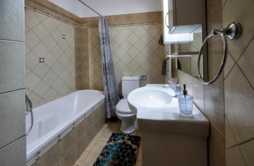 a bathroom with a sink and a tub and a toilet at Swan Lake Front Apartment in Kastoria