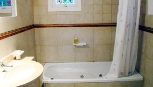 y baño con bañera, lavamanos y cortina de ducha. en Manzanauno 108 en Mar de las Pampas