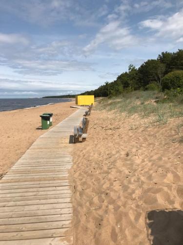 une rangée de bancs sur une promenade en bois sur une plage dans l'établissement Baņuta_2, à Saulkrasti