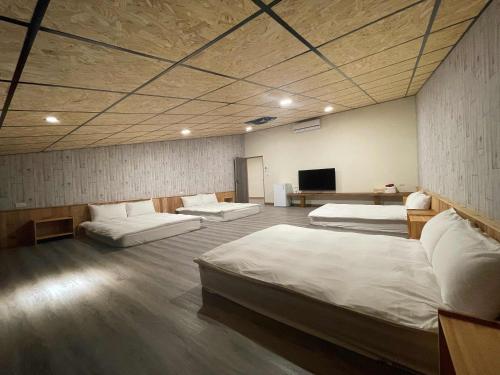 a room with three beds and a flat screen tv at Qilin Valley in Puli