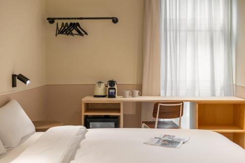 1 dormitorio con cama, escritorio y ventana en La Florida Suites by Olala Homes, en Hospitalet de Llobregat