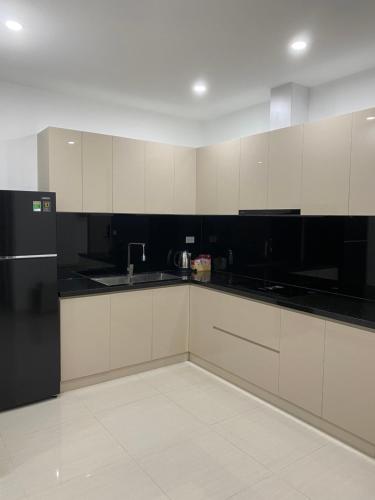 a kitchen with white cabinets and a black refrigerator at Mô Tê Huế Homestay in Hue