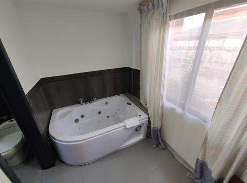 a white bath tub in a bathroom with a toilet at Villa Cosmopolita in Baños