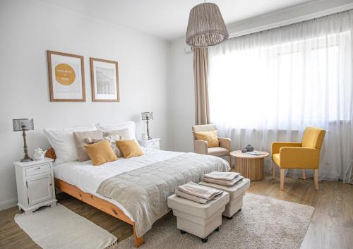 a white bedroom with a large bed and two chairs at Cozy Airport in Vecsés