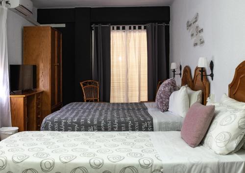 a hotel room with two beds and a window at Hostal Victoria in Altura