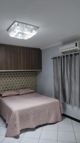 - une chambre avec un lit et un lustre dans l'établissement Casa bairro Tiradentes, à Governador Valadares