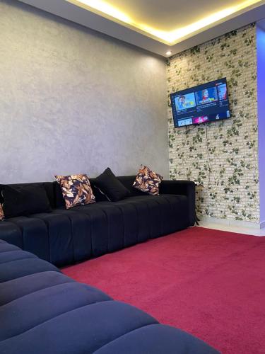 sala de estar con sofá negro y TV en holiday and beach self check-in en Agadir