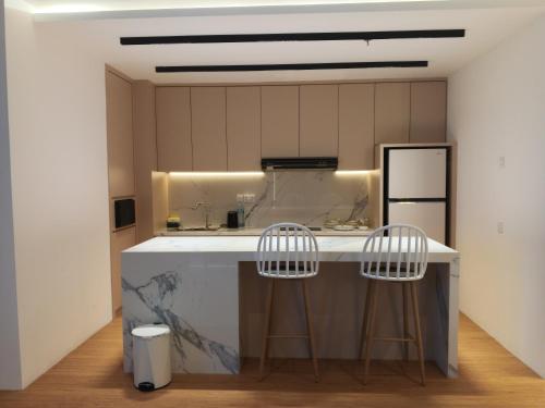 cocina con encimera blanca y 2 taburetes en Formosa Spacious Apartments with Netflix & Free Shuttle by MESA, en Nagoya