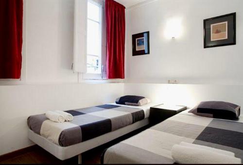 Habitación con 2 camas y ventana con cortinas rojas. en 5-bed apartment in the heart of the city en Barcelona