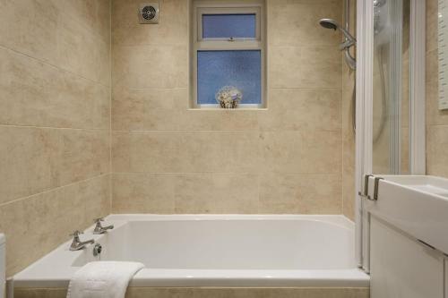ein Bad mit einer Badewanne und einem Fenster in der Unterkunft Eastney Escape in Portsmouth