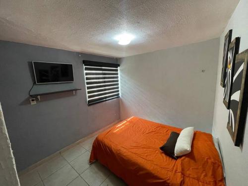 Schlafzimmer mit einem orangenen Bett und einem TV in der Unterkunft Casa Luxxury Celaya in Celaya
