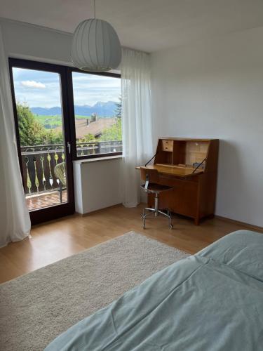a bedroom with a bed and a desk and a window at Helle Wohnung mit großem Balkon in Oberreute
