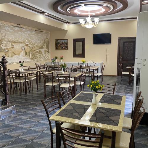 a restaurant with tables and chairs and a wall with a mural at VOSTOK HOTEL in Bukhara